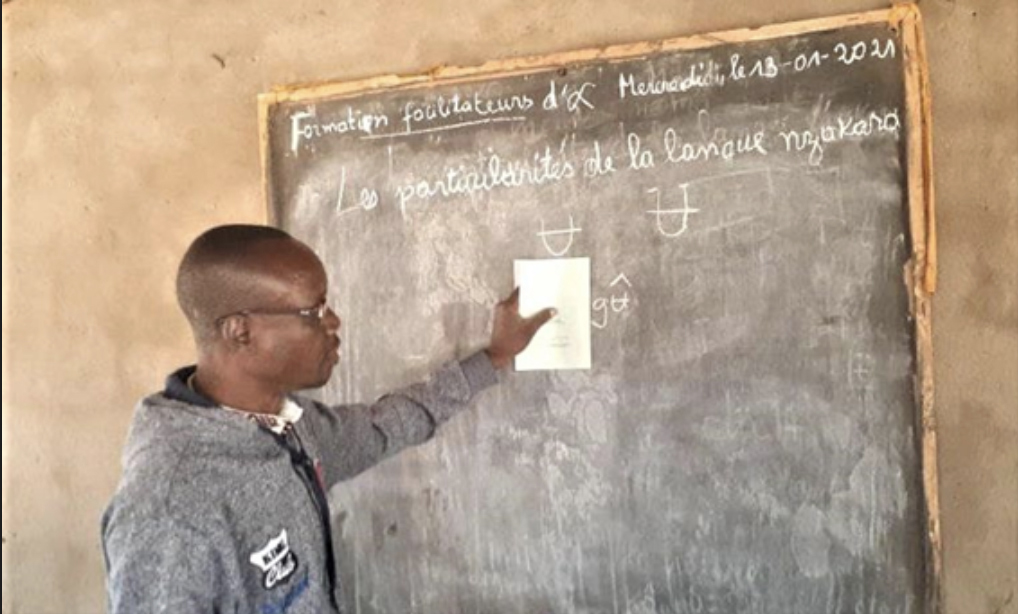 A man points to a chalkboard