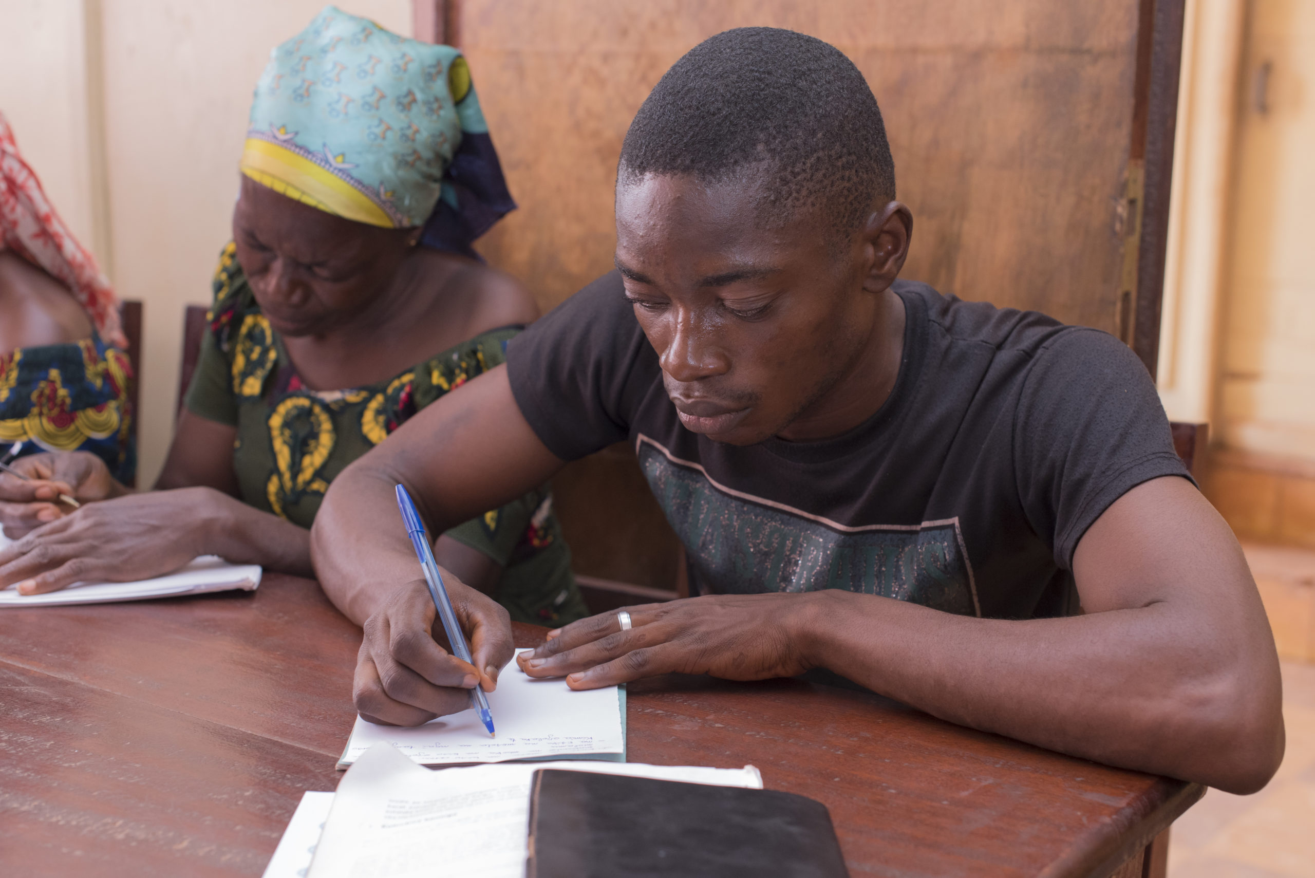 A man and a woman sit at a table writing laments