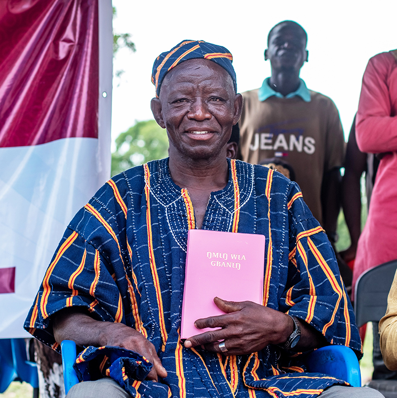 Image of a Koma man holding the Koma Bible