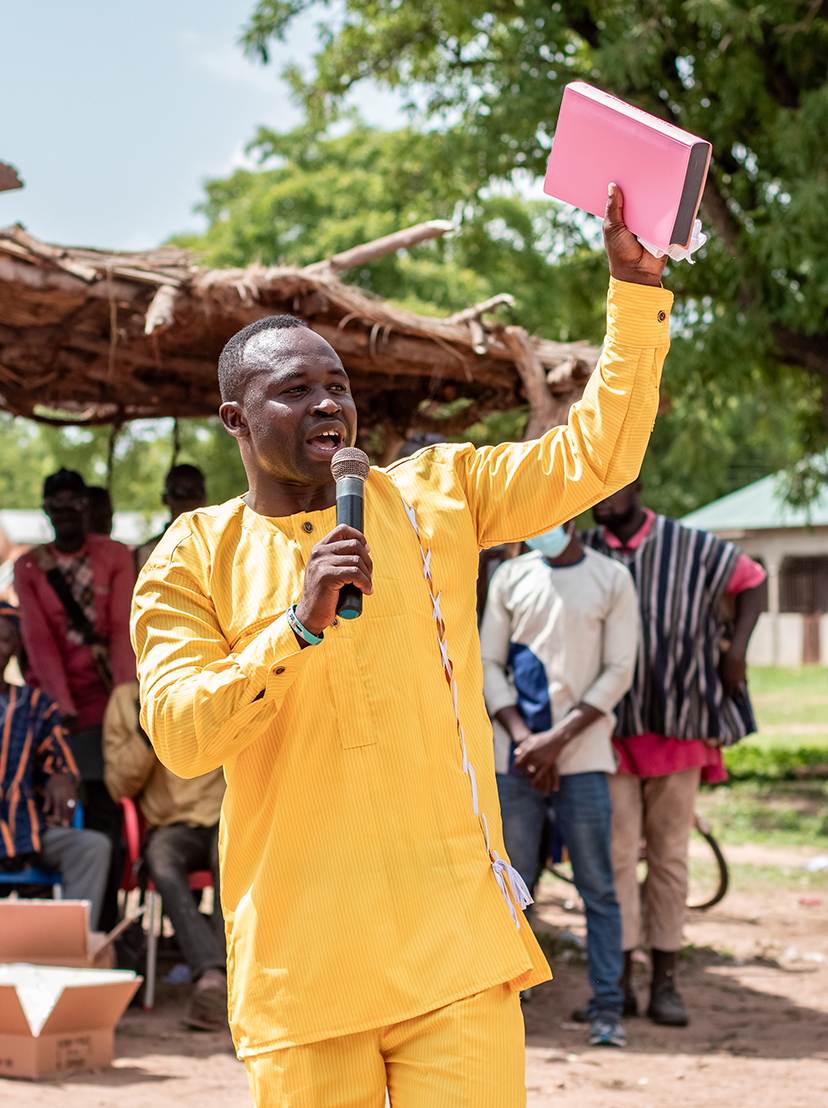 Image of Yisifu, one of the Koma pastors, holding up the Koma Bible