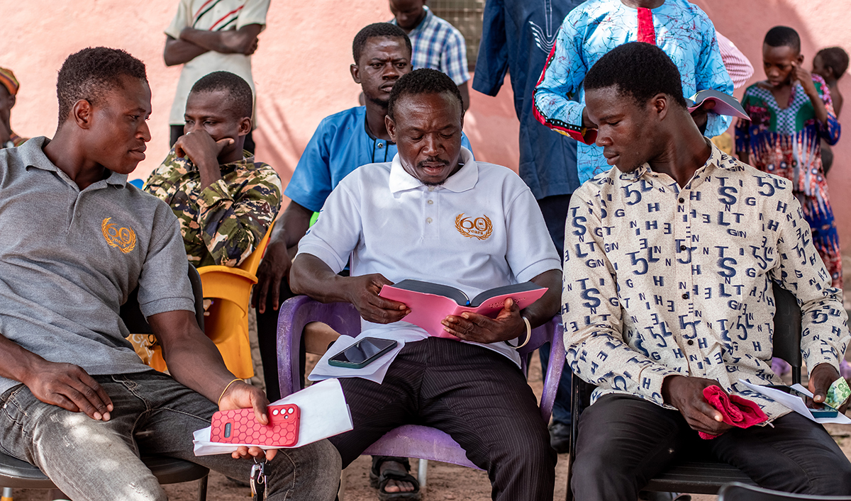 Image of three Koma men looking at the Koma Bible