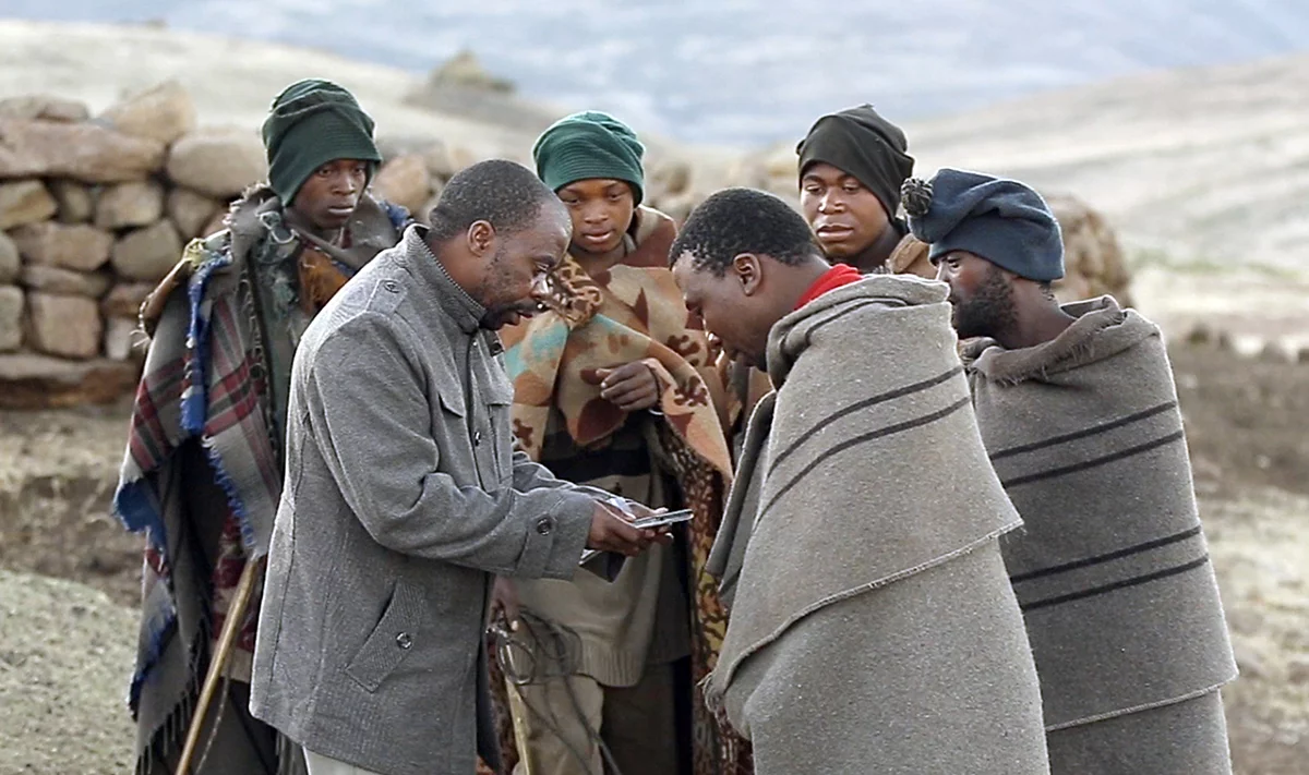 Image of a group of men listening to the Scriptures on an audio player