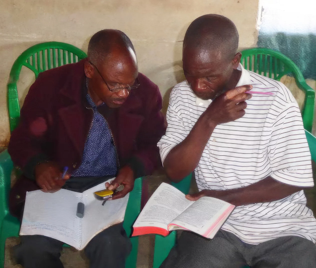 Two Malila people consider the New Testament in print and audio forms at a workshop